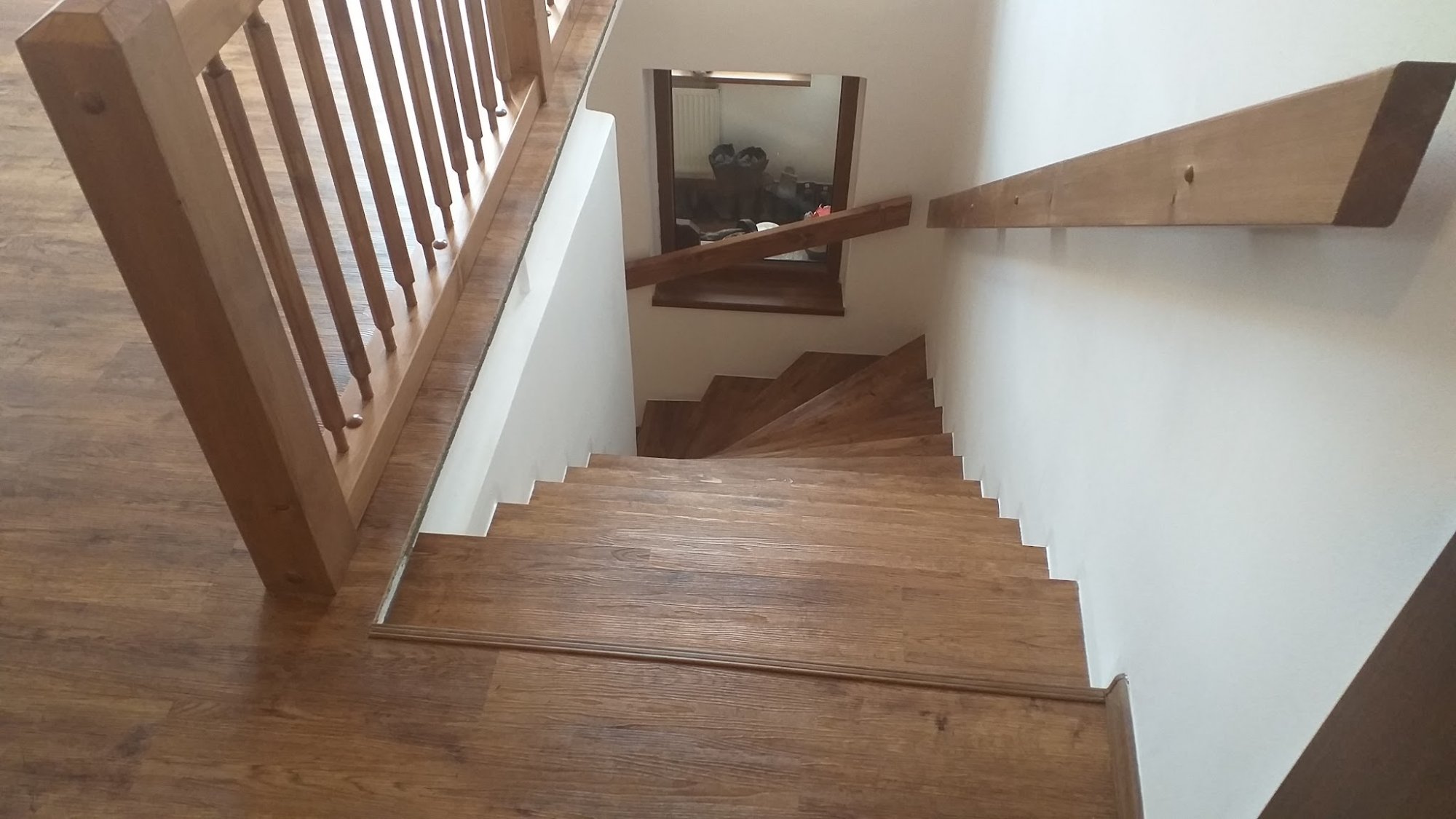 Točité schodiště s laminátovými nášlapy a dřevěným zábradlím